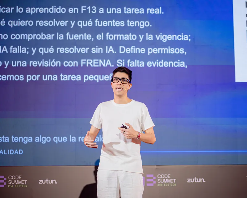 Sebastian Bimbi speaking in front of a blue presentation screen at F13 Code Summit.